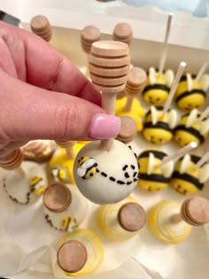 a person is holding a small toy in front of some cake pops and honeybees