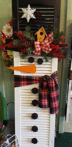 a snowman made out of an old shutter and some christmas wreaths on it