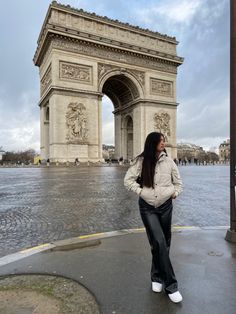 a woman standing in front of the arc de trio triumph