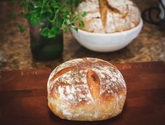 a loaf of bread sitting on top of a wooden cutting board next to a potted plant