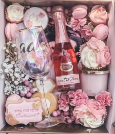 a pink box filled with cupcakes, wine glasses and other decorative items in it