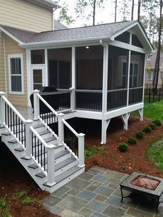 a house with a porch and stairs leading up to the front door, next to a fire pit