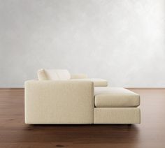 a white couch sitting on top of a wooden floor next to a wall and window