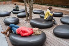 a woman laying on top of a black bean bag chair