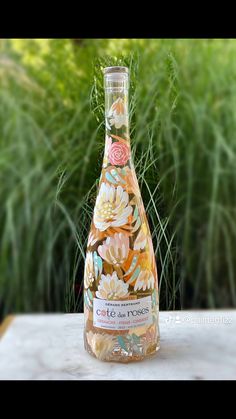 a bottle of wine sitting on top of a table next to some grass and bushes