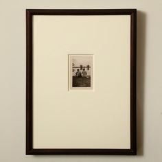 a black and white photo hanging on the wall next to a brown framed artwork piece