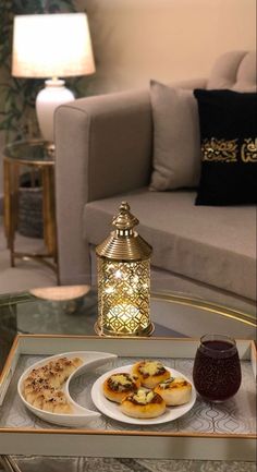 a glass table topped with plates of food and a candle next to a couch in a living room