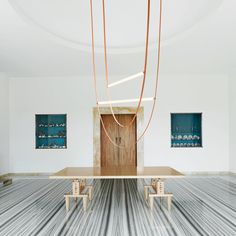 an empty room with paintings on the wall and a table in the middle, surrounded by chairs