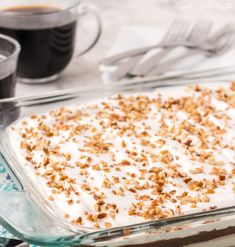 a glass dish filled with food next to two cups of coffee