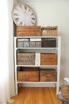 a white book shelf filled with boxes next to a clock on top of a wall