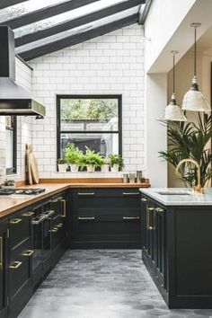 a kitchen with black cabinets and white brick walls is pictured in this image, there are potted plants on the counter