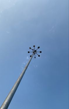 a tall pole with four lights on top against a blue sky and some clouds in the background