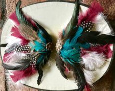 This beautiful headpiece was handcrafted with rooster feather, guinea feathers, domestic turkey feathers, and duck feathers.  Sold as a pair, but can be worn together or one at a time.  Brass floral detail finish off the design. Wear one behind the each ear or together at the nape of the neck for a glamorous and festive presentation.  One wear one at a time.  Alligator clips hold the pieces in place. Feather Hair Pieces, Maroon And Green, Green Feather, Rooster Feathers, Feather Hair, Turkey Feathers, Alligator Clips, Feathered Hairstyles, Costume Hats