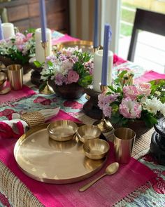 the table is set with gold dishes and pink napkins, candles, and flowers