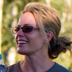 a woman wearing sunglasses and holding a water bottle