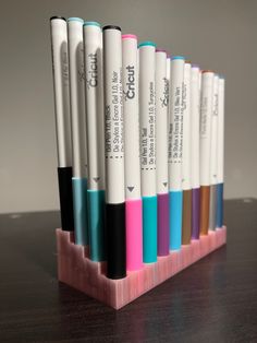 a row of pens sitting on top of a wooden desk next to each other in different colors