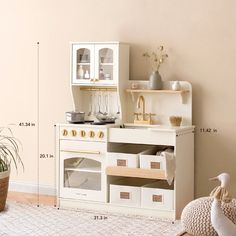 a white toy kitchen with lots of drawers and cupboards on the wall next to it