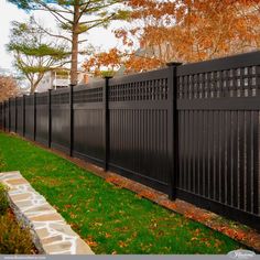 a black fence in the middle of a grassy area with trees and leaves around it