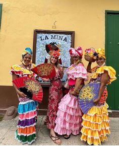 three women in colorful dresses are posing for the camera