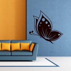 a living room with a blue couch and yellow pillows on the floor in front of a butterfly wall decal