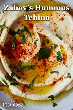 hummus served in a white bowl with herbs on top