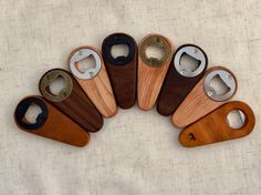 six wooden bottle openers are arranged in a circle on a white surface with one open and the other closed