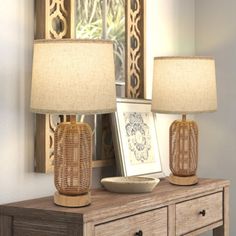 two lamps sitting on top of a wooden table next to a mirror and lamp shade