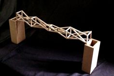 a model of a bridge made out of cardboard on a black background with a dark backdrop