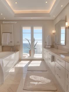 a large bathroom with two sinks and a bathtub next to a window overlooking the ocean