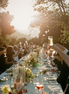 a long table with many people sitting at it and some glasses on top of it