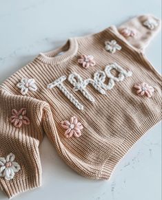 a knitted sweater with flowers and the word hope on it is laying on a table