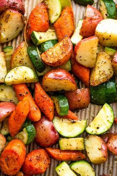 potatoes, zucchini and carrots are on a tray with some seasoning