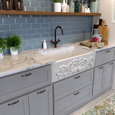 a kitchen with gray cabinets and marble counter tops