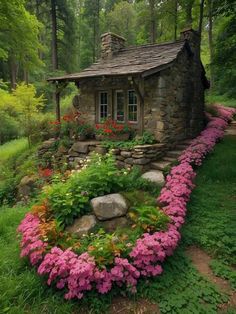 a small stone house surrounded by flowers and greenery in the middle of a forest