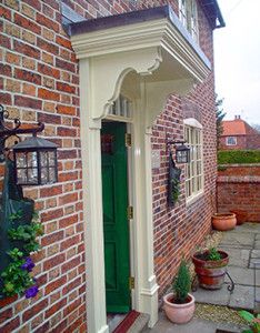 a green door is on the side of a red brick building with potted plants