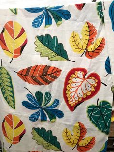 an oven mitt with colorful leaves on it and a heart shaped dish towel hanging from the side