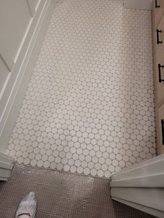 a bathroom with white and gray tile on the floor next to a cabinet in the corner