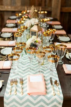 a long table set with gold and silver place settings, pink napkins, and glasses