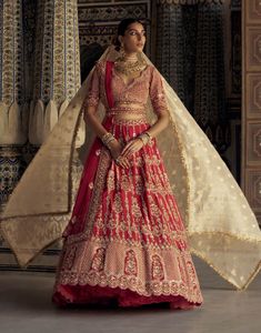 A captivating blood-red raw silk lehenga with a net dupatta, featuring gold kasab embroidery and delicate resham French knots, patras, dabka, beads, and sequins. It comes with a gold tissue stripe booti dupatta and embellished belt. Kasab Embroidery, Red Silk Lehenga, Embroidered Bridal Lehenga, White Lehenga, Raw Silk Lehenga, Patras, Diana Penty