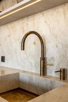 a kitchen with marble counter tops and gold faucets