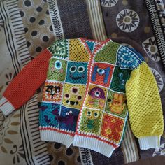 a colorful sweater is laying on top of a bed with an animal pattern and eyes