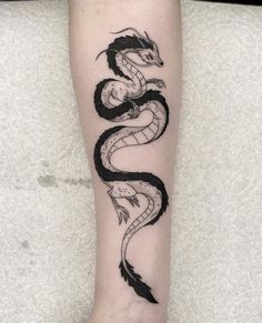 a black and white dragon tattoo on the right forearm, with an arrow in the middle