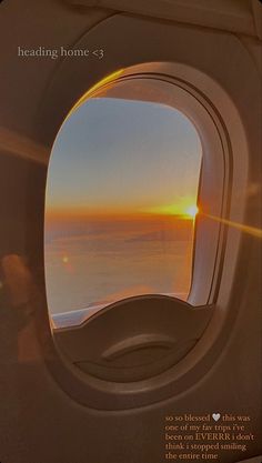 an airplane window with the sun setting in the sky and clouds visible from inside it