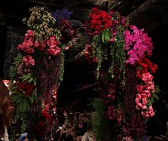 a bunch of flowers that are on some kind of stage with people watching and taking pictures