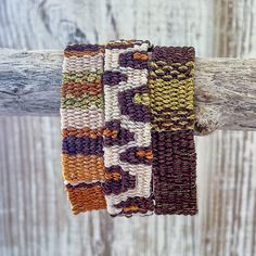 three woven bracelets hanging on a wooden stick