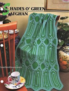 a green afghan sitting on top of a table next to a cup and saucer