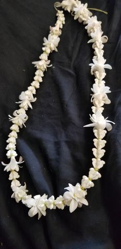 a white flower necklace on a black cloth