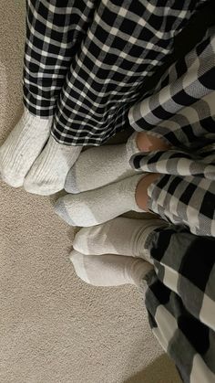 two people standing on the floor with their feet up in checkered pants and socks