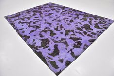 a purple and black area rug sitting on top of a white floor