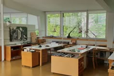 a room filled with lots of wooden desks and chairs next to large open windows